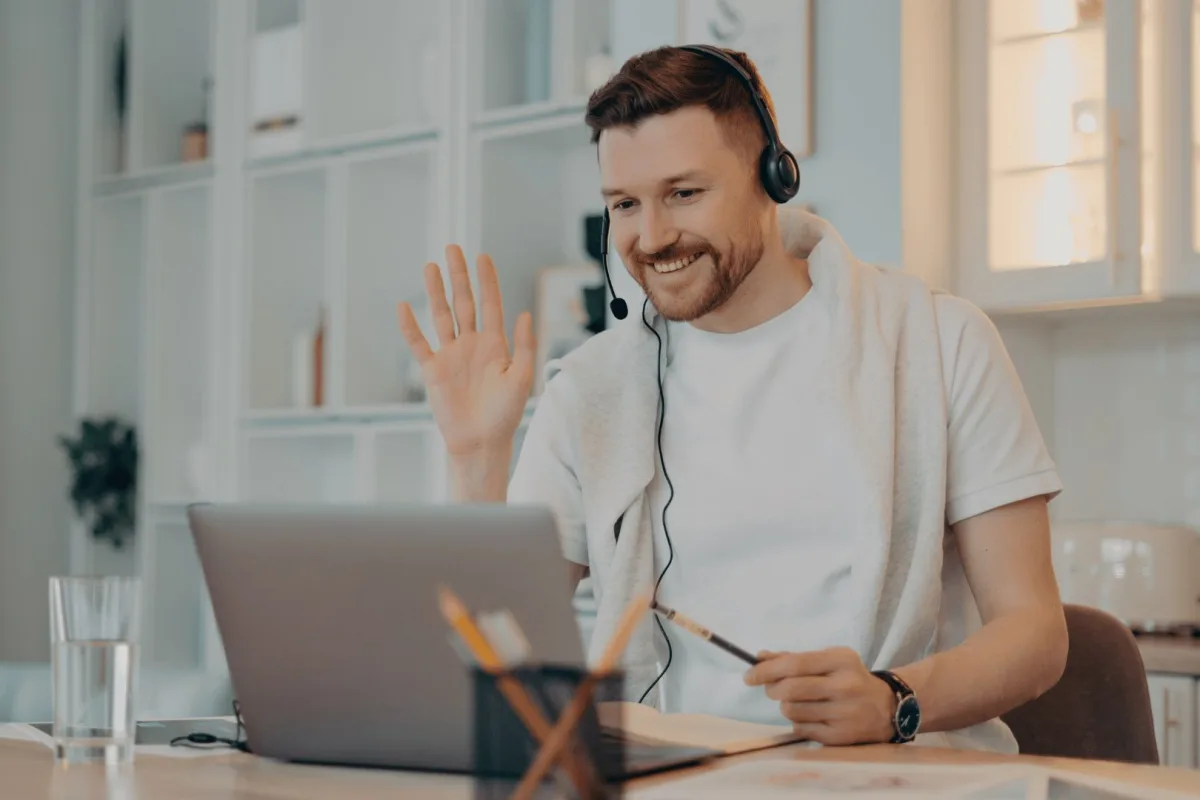 Un homme équipé d’un casque salue son coach en visio depuis son bureau